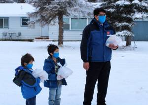 Carter Kyle (left), Lincoln Kyle (center) and Brandon Kyle (right) hand off Thanksgiving meals at a drive through event hosted by the Salvation Army on Thursday, Nov. 25, 2021 in Kenai, Alaska. (Ashlyn OHara/Peninsula Clarion)