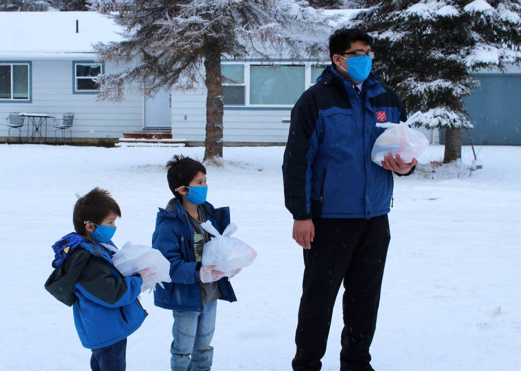 Carter Kyle (left), Lincoln Kyle (center) and Brandon Kyle (right) hand off Thanksgiving meals at a drive through event hosted by the Salvation Army on Thursday, Nov. 25, 2021 in Kenai, Alaska. (Ashlyn O'Hara/Peninsula Clarion)