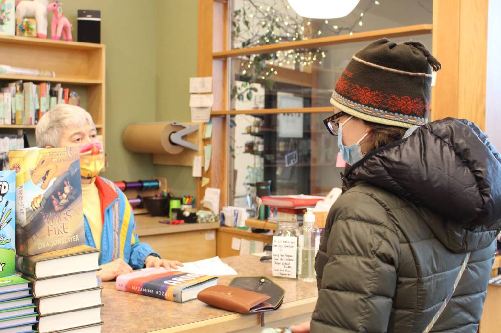 Maria Dixson, left, rings up a purchase by Sarah Pyhala, right, at River City Books in Soldotna, Alaska, on Jan. 2, 2021. (Photo by Brian Mazurek/Peninsula Clarion file)