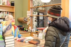 Maria Dixson, left, rings up a purchase by Sarah Pyhala, right, at River City Books in Soldotna, Alaska, on Jan. 2, 2021. (Photo by Brian Mazurek/Peninsula Clarion file)