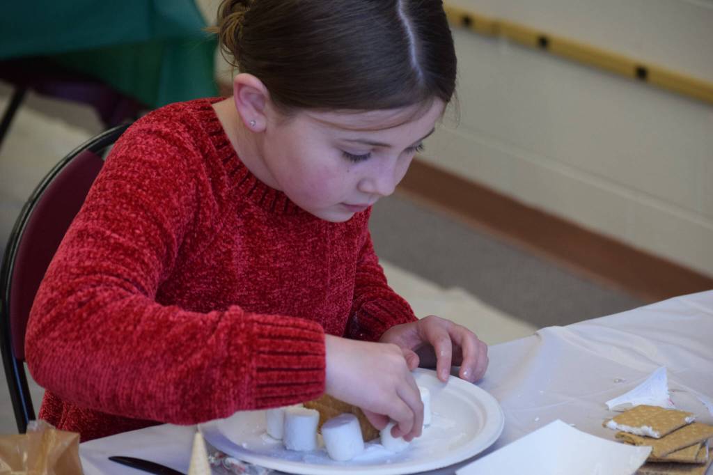 Adalynn Kouns makes a homemade gingerbread house at the Nikiski Community Recreation Center on Saturday, Dec. 11, 2021, in Nikiski, Alaska. (Camille Botello/Peninsula Clarion)