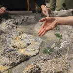 Kenai Watershed Forum media coordinator Galen Hecht uses a river table to explain how watersheds impact their surroundings during a demonstration given at the Donald E. Gilman River Center on Tuesday, Dec. 14, 2021 in Soldotna, Alaska. (Ashlyn OHara/Peninsula Clarion)