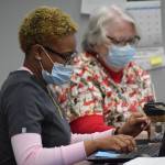 Certified nursing assistant KaDaisjah Roberts, left, and nurse Debbie Aubin, right, work at the Y vaccine clinic in Soldotna on Dec. 22, 2021. (Camille Botello/Peninsula Clarion)