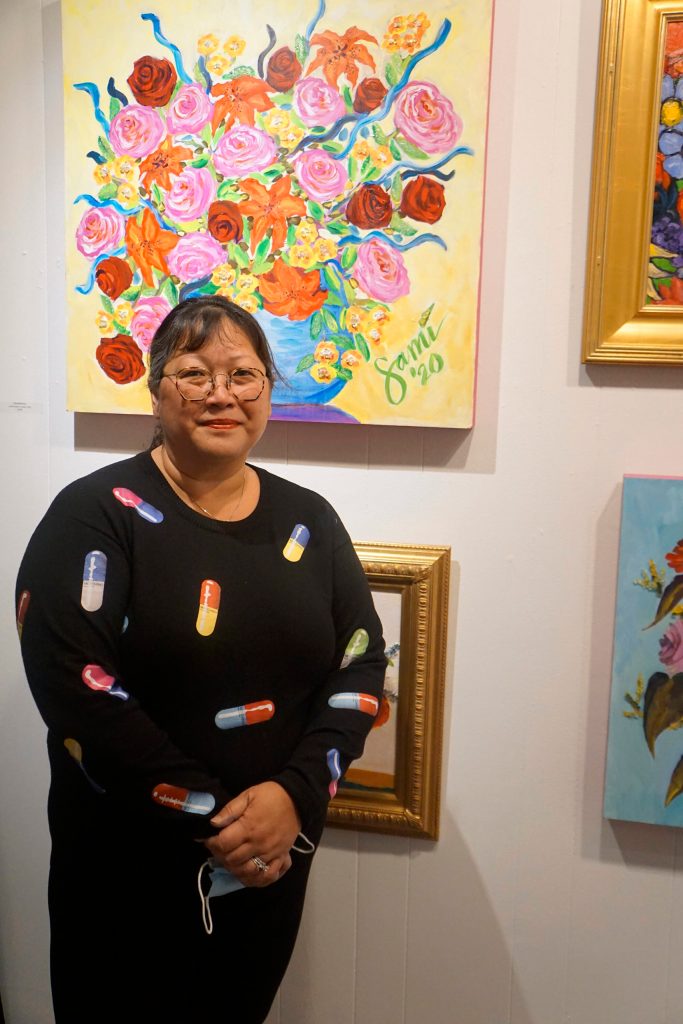 Dr. Sami Alis poses in front of some her paintings in her show, The Mind of a Healthcare Worker During the COVID-19 Pandemic, on Friday, Jan, 7, 2022, at the Homer Council on the Arts in Homer, Alaska. (Photo by Michael Armstrong/Homer News)