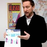 FILE - Former Alaska lawmaker Jason Grenn holds an Alaska Division of Elections brochure explaining ranked choice voting at his office in Anchorage, Alaska, on Friday, Jan. 14, 2022. The Alaska Supreme Court has upheld as valid a voter-approved election system that would end party primaries in the state and institute ranked choice voting in general elections. A brief order released Wednesday, Jan. 19, 2022, affirmed a lower court ruling from last year. (AP Photo/Mark Thiessen, File)