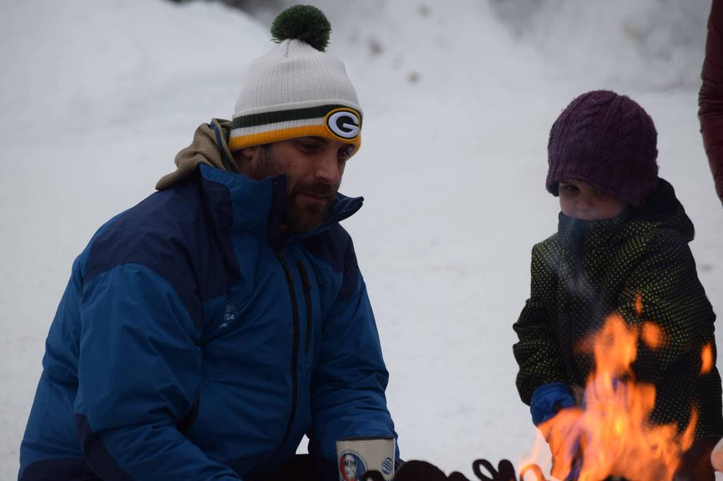 Branden Bornemann (left) and Axel Savage celebrate the 25th anniversary of the Kenai Watershed Forum by roasting marshmallows on Thursday, Jan. 20, 2022. (Camille Botello/Peninsula Clarion)