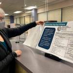 Deborah Moody, an administrative clerk at the Alaska Division of Elections office in Anchorage, Alaska, looks at an oversized booklet explaining election changes in the state on Jan. 21, 2022. Alaska elections will be held for the first time this year under a voter-backed system that scraps party primaries and sends the top four vote-getters regardless of party to the general election, where ranked choice voting will be used to determine a winner. No other state conducts its elections with that same combination. (AP Photo/Mark Thiessen)