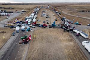 Anti-COVID-19 vaccine mandate demonstrators gather as a truck convoy blocks the highway at the busy U.S. border crossing in Coutts, Alberta, Canada, Monday, Jan. 31, 2022. (Jeff McIntosh/The Canadian Press via AP)