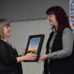 Monica Frost accepts the Soldotna Chamber of Commerces Excellence in profession award from Sara Hondel on behalf of Joe Moore of the Altman, Rogers Co. certified public accounting firm, during the chambers 2021 award ceremony at the Soldotna Sports Complex on Wednesday, Feb. 9, 2022. (Camille Botello/Peninsula Clarion)