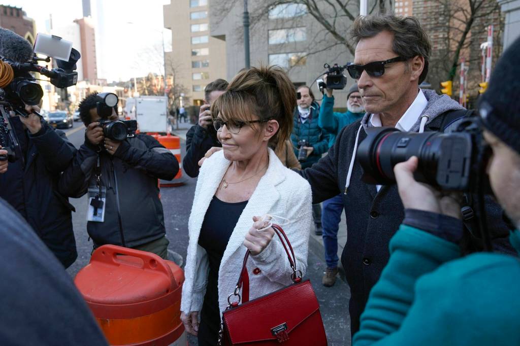 Sarah Palin is escorted to her car by Ron Duguay after leaving the courthouse in New York, Thursday, Feb. 10, 2022. Former Alaska Gov. Sarah Palin told a jury Thursday she felt like she was at the mercy of a “Goliath” when she first learned a 2017 New York Times editorial suggested her campaign rhetoric helped incite a mass shooting.(AP Photo/Seth Wenig)