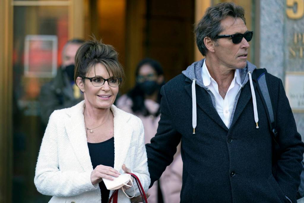 Sarah Palin is escorted to her car by Ron Duguay after leaving the courthouse in New York, Thursday, Feb. 10, 2022. Former Alaska Gov. Sarah Palin told a jury Thursday she felt like she was at the mercy of a “Goliath” when she first learned a 2017 New York Times editorial suggested her campaign rhetoric helped incite a mass shooting.(AP Photo/Seth Wenig)