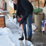 Josh Lingle shovels outside Ye Olde Curiosity Shoppe after overnight freezing rain brought icy conditions to Kenai on Wednesday, Feb. 16, 2022. (Camille Botello/Peninsula Clarion)