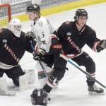 Kenai River Brown Bears forward Nick Stevens and Minnesota Magicians defenseman Evan Tanos battle for the puck in front of Minnesota Magicians goalie Josh Seeley on Friday, Feb. 25, 2022, at the Soldotna Regional Sports Complex in Soldotna, Alaska. (Photo by Jeff Helminiak/Peninsula Clarion)