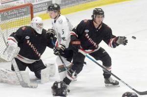 Kenai River Brown Bears forward Nick Stevens and Minnesota Magicians defenseman Evan Tanos battle for the puck in front of Minnesota Magicians goalie Josh Seeley on Friday, Feb. 25, 2022, at the Soldotna Regional Sports Complex in Soldotna, Alaska. (Photo by Jeff Helminiak/Peninsula Clarion)
