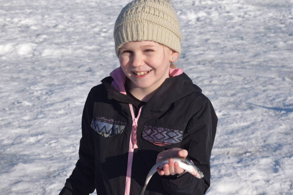 Aurora Borealis Charter School third grader Moriah Hodges poses with her catch of the day while ice fishing at Sport Lake as part of the Alaska Department of Fish and Games Salmon in the Classroom ice fishing educational program on Wednesday, March 2, 2022, in Soldotna. (Camille Botello/Peninsula Clarion)