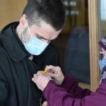 Kim Keck gives James Redmon a crochet sunflower pendant during the Many Voices Ukraine vigil on Saturday, March 5, 2022, in Soldotna, Alaska. (Camille Botello/Peninsula Clarion)