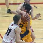 Nikolaevsks Lukah Kalugin drives between Kenai Centrals Luke Armstrong and Wade James on Saturday, March 5, 2022, at Kenai Central High School in Kenai, Alaska. (Photo by Jeff Helminiak/Peninsula Clarion)