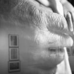 Lisa Williams photography exhibit is reflected in the glass of a print for her photo, Nick Tanape Sr. and grandson, as seen at the Pratt Museum & Park on Feb. 28, 2022, in Homer, Alaska. (Photo by Sean McDermott)