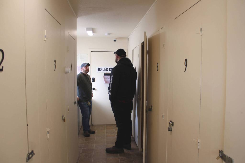 Tyson Cox (left) speaks to potential tenants in a laundry and storage facility at an apartment building on Tuesday, March 22, 2022, in Soldotna, Alaska. (Ashlyn OHara/Peninsula Clarion)