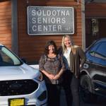 Soldotna Senior Center Executive Director Loretta Knudson-Spalding, left, and Jill Schaefer, regional director of the Office of the Governor, pose next to the senior centers new cars in Soldotna, Alaska, on Wednesday, March 30, 2022. (Camille Botello/Peninsula Clarion)
