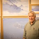 Photo by Sean McDermott 
David Rosenthal poses for a portrait in front of paintings from his time in Antarctica at the Pratt Museum & Park in Homer.