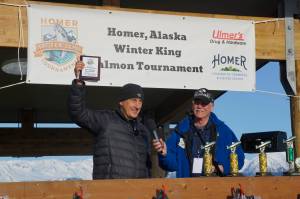 Jay Marley, left, captain of the Fly Dough, holds up the John Hillstrand Memorial Award for running the boat that had the winning fish in the 28th annual Homer Winter King Salmon Tournament. Homer Chamber of Commerce and Visitor Center executive director Brad Anderson is at right. Marleys son, Weston Marley, won the top prize with a 27.38-pound king salmon. Jay Marley also was the top captain in 2021 when his son Andrew also won the tournament. (Photo by Michael Armstrong/Homer News)
