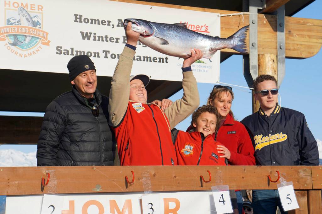 Weston Marley, second from left, holds up the 27.38-pound winter king salmon he caught to win the 28th annual Homer Winter King Salmon Tournament on Sunday, April 10, 2022, in Kachemak Bay, Homer, Alaska. Marley, 15, fished on the Fly Dough with his father, Jay Marley, left, and brother, Andrew Marley, center. Joining them are Zach Marley, far right, and mom Erica Marley, second from right. It's the second year a Marley boy won the tournament, with Andrew taking first place for a 25.62-pound king in 2021. (Photo by Michael Armstrong/Homer News)