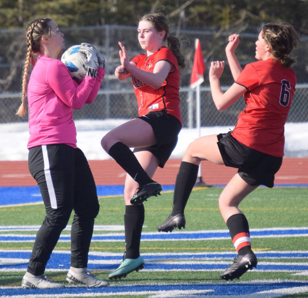 Soldotna goalie Sunny Miller makes a save in front of Kenai Centrals Tait Cooper and Kori Moore on Thursday, April 14, 2022, at Soldotna High School in Soldotna, Alaska. (Photo by Jeff Helminiak/Peninsula Clarion)