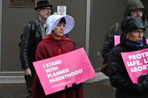Peter Segall / Juneau Empire
Lisa Denny wears The Handmaids Tale-inspired garb while holding a sign stating I stand with Planned Parenthood during a protest held near the Alaska State Capitol on Tuesday, May 3, following a leaked draft of a Supreme Court decision that would overturn the landmark case Roe v. Wade.