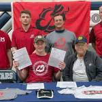Wayne Mellon, seated at the table with stepfather Michael Gebhard, signs a National Letter of Intent on Tuesday, May 4, 2022, at Soldotna High School in Soldotna, Alaska. In back are SoHi wrestling coaches Aaron Gordon, Logan Parks, Neldon Gardner and Pete Dickinson. (Photo provided)