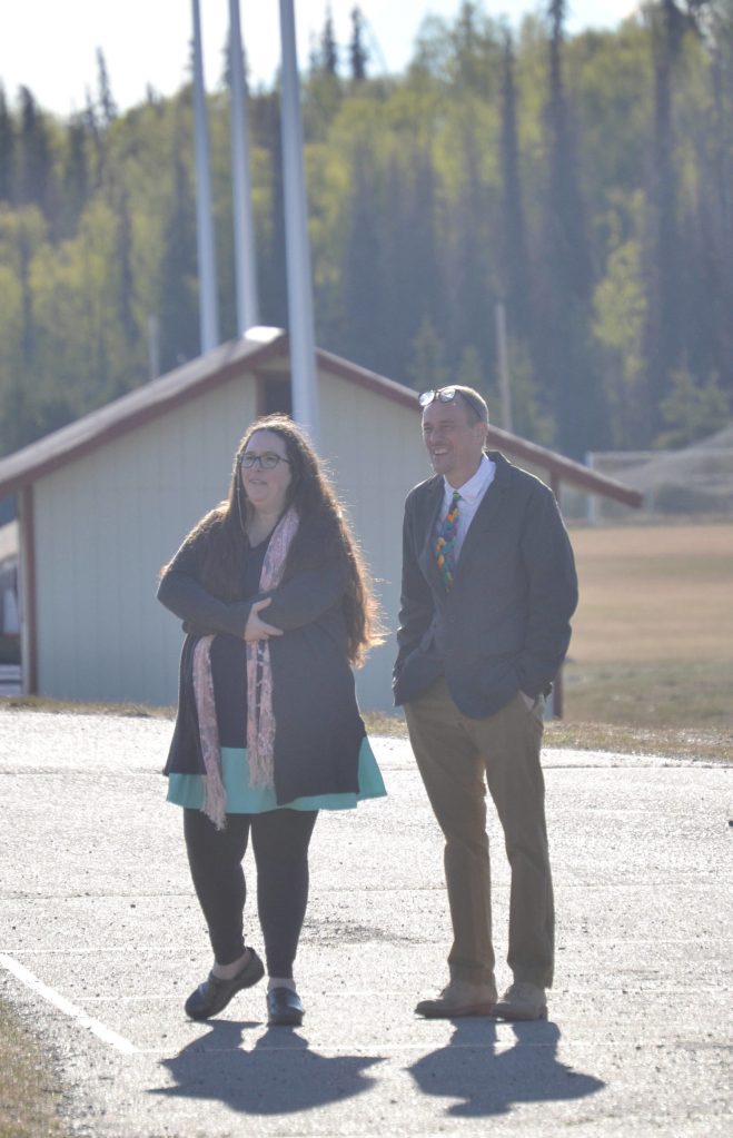 Dawn Edwards-Smith and Tad DeGray, two original staff members at River City Academy who are retiring, pause to look back at graduation ceremonies after taking a walk into the sunset Tuesday, May 17, 2022, outside of Skyview Middle School just outside of Soldotna, Alaska. (Photo by Jeff Helminiak/Peninsula Clarion)
