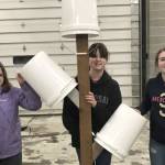 Three Girl Scouts from Troop 210 hold their first Bucket Tree after finishing construction with the help of Davis Block employees. (Photo by Leah Eskelin)