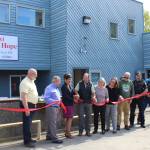 Project stakeholders cut a ribbon at the Nikiski Shelter of Hope on Friday, May 20, 2022, in Nikiski, Alaska. (Ashlyn OHara/Peninsula Clarion)