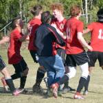 The Kenai Central boys soccer teams mobs Joe Hamilton (center) after Hamilton scored the game-winning penalty kick in the Peninsula Conference championship game Saturday, May 21, 2022, at Nikiski High School in Nikiski, Alaska. (Photo by Jeff Helminiak/Peninsula Clarion)