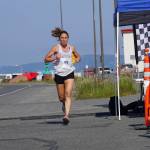 Aleah Mickelson, the first-place woman in the 2022 Homer Spit Run Half Marathon, crosses the finish line on Saturday, June 25, 2022, at the End of the Road Park in Homer, Alaska. (Photo by Michael Armstrong/Homer News)