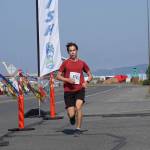 Evan Markelz, the first-place man in the 2022 Homer Spit Run 10k, crosses the finish line on Saturday, June 25, 2022, at the End of the Road Park in Homer, Alaska. (Photo by Michael Armstrong/Homer News)
