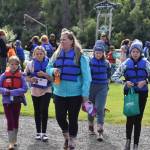 A group of children and a chaperone, fitted with life jackets and waiting to go fishing at the Kenai River Junior Classic in Soldotna, Alaska, on Aug. 10, 2022. (Jake Dye/Peninsula Clarion)