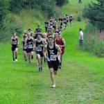 Kenai Central junior Greg Fallon takes the lead for good at the Kenai-Soldotna dual meet Monday, Aug. 15, 2022, at Tsalteshi Trails just outside of Soldotna, Alaska. (Photo by Jeff Helminiak/Peninsula Clarion)