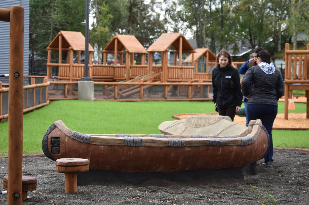 Members of a tour at the Kahtnuhtana Duhdeldiht Campus check out the birch bark canoe and kayak on the playground on Thursday, Sept. 1, 2022, in Kenai, Alaska. (Jake Dye/Peninsula Clarion)