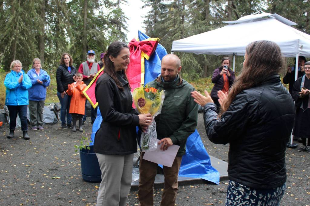 Artist Christina Demetro, right, presents Sarah Pyhala, left, and Matthew Pyhala, center, with flowers at the grand opening of the Kenai Peninsula Peace Crane Garden Trails on Thursday, Sept. 8, 2022, in Soldotna, Alaska. (Ashlyn OHara/Peninsula Clarion)