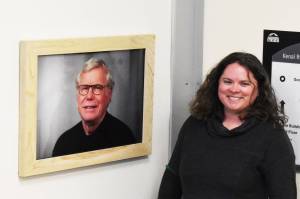 Kenai Peninsula College Advancement Programs Manager Alasha Brito unveils a new framed photo that hangs at the entryway of the newly dedicated Alan Tiqutsex Boraas Anthropology Lab at KPC on Friday, Sept. 16, 2022, in Soldotna, Alaska. A new plaque and a piece of artwork to commemorate Boraas also hang by the entryway. (Jake Dye/Peninsula Clarion)