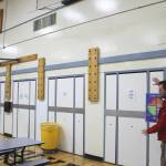 Soldotna Elementary School Principal Dr. Austin Stevenson gestures to lunch tables that are nailed into the gym wall on Friday, Sept. 30, 2022, in Soldotna, Alaska. (Ashlyn OHara/Peninsula Clarion)