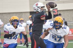 Kenai Central's Bridger Beck passes under pressure from Barrow's Lennox Dias and Norm Lilomaiava on Saturday, Oct. 1, 2022, at Ed Hollier Field at Kenai Central High School in Kenai, Alaska. (Photo by Jeff Helminiak/Peninsula Clarion)