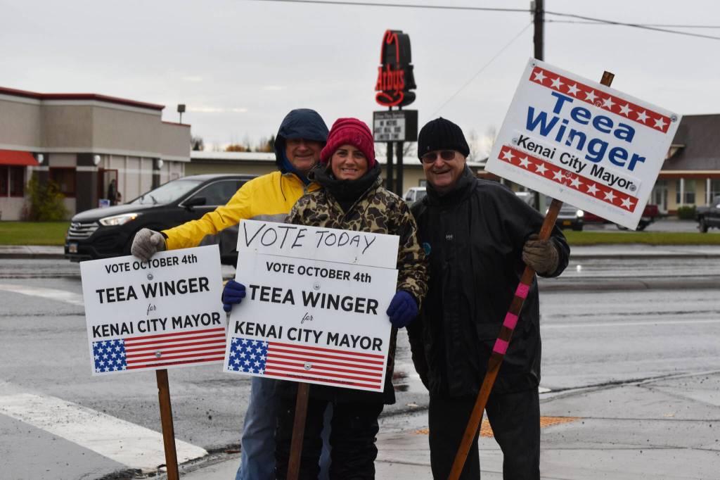 Mike McBride, Teea Winger and Jim Glendening wave signs on Election Day, Oct. 4, 2022, in Kenai, Alaska. (Jake Dye/Peninsula Clarion)