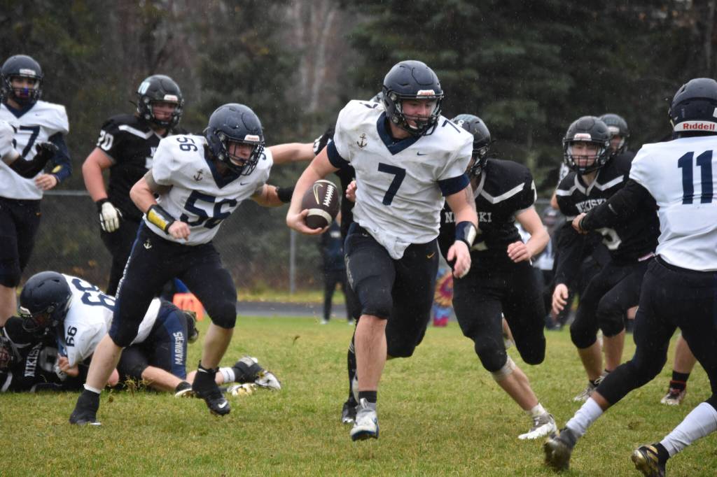 Homers Carter Tennison runs with the ball, pursued by several Bulldogs, during the playoff game on Saturday, Oct. 8, 2022, at Nikiski Middle/High School in Nikiski, Alaska. (Jake Dye/Peninsula Clarion)
