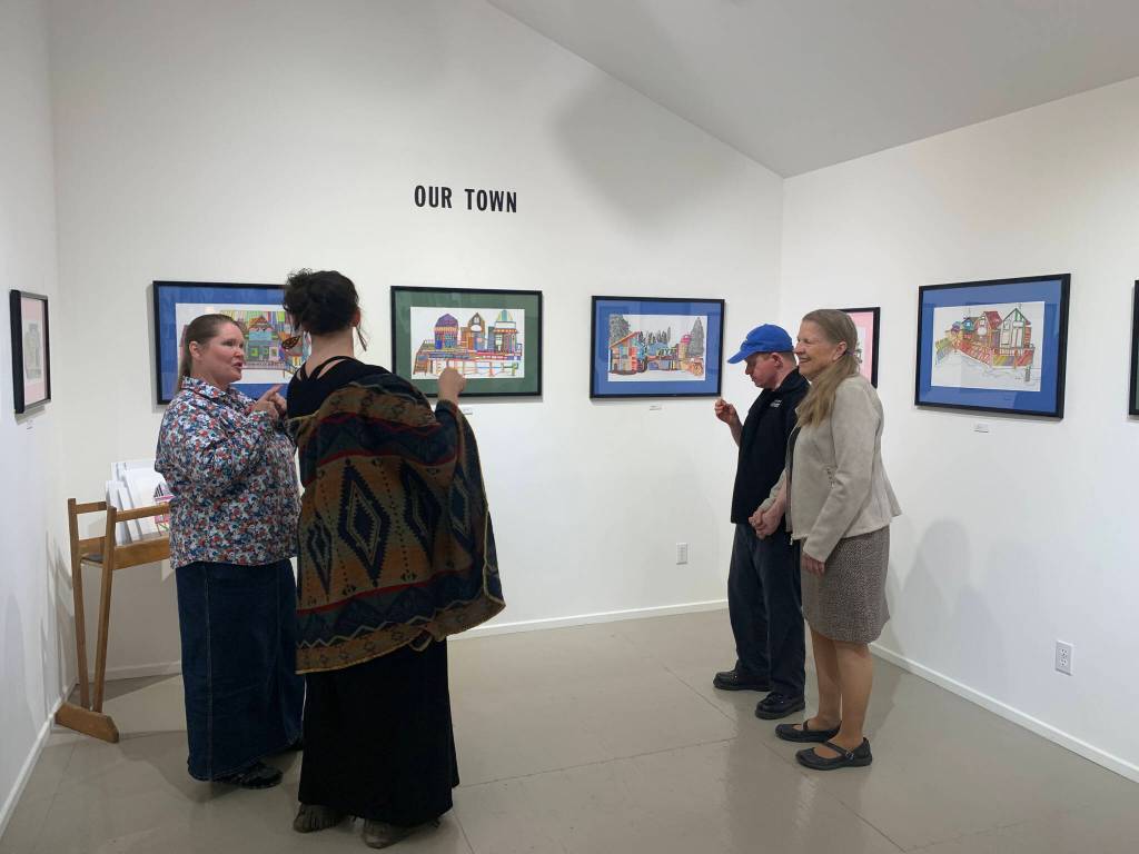 A community member discusses the exhibit with artist Teresa Aldridge while collaborating artist Erik Behnke and his mother, Linda Thomspon, look on, Friday, Oct. 7, 2022, in Homer, Alaska. (Photo by Christina Whiting/Homer News)
