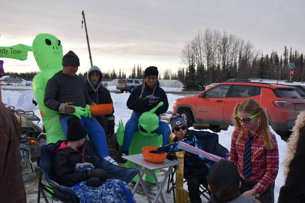 Despite being abducted by aliens, a family gives candy to children at the Orca Theaters Trunk or Treat in Soldotna, Alaska, on Monday, Oct. 31, 2022. (Jake Dye/Peninsula Clarion)