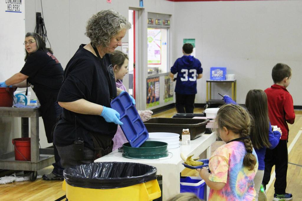 Principal Denise Kelly helps students dispose of lunch materials at Sterling Elementary School on Thursday, Nov. 10, 2022, in Sterling, Alaska. (Ashlyn OHara/Peninsula Clarion)