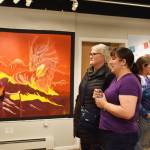 Theresa Ritter, an artist with a piece in the exhibition, speaks to an attendee of the Mural 2022 opening reception at Kenai Art Center in Kenai, Alaska, on Thursday, Nov. 10, 2022. (Jake Dye/Peninsula Clarion)