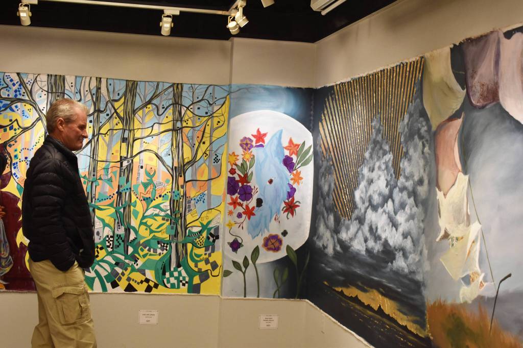 An attendee of the opening reception for the Mural 2022 exhibition views this years mural at the Kenai Art Center in Kenai, Alaska, on Thursday, Nov. 10, 2022. (Jake Dye/Peninsula Clarion)